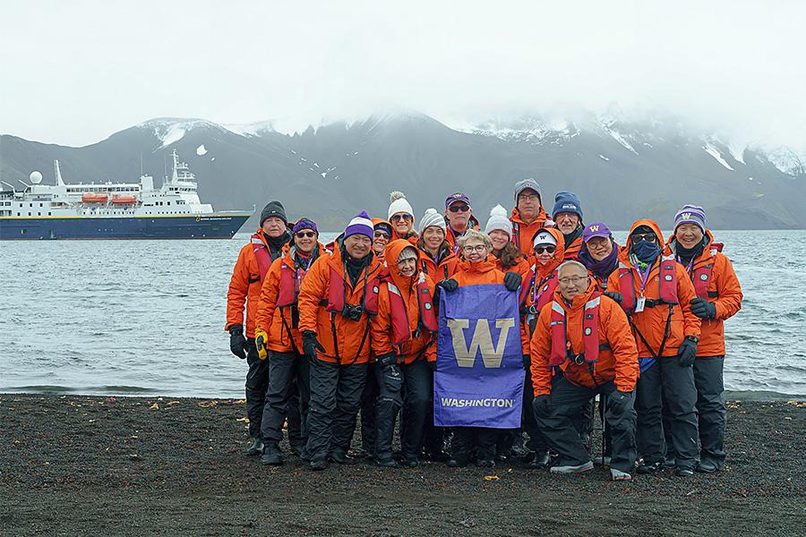 Group of Husky travelers in Antarctica, posting with a purple W flag.